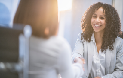 An Exec congratulates a diverse leader in an office setting observing good Emotional Intelligence